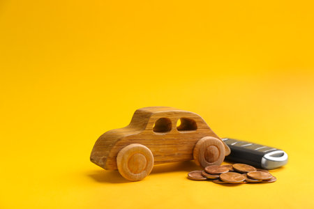 Wooden car model, key and coins on color background. Space for textの写真素材