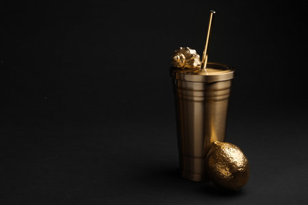 Gold cup with seashell and lemon on black background. Space for textの写真素材
