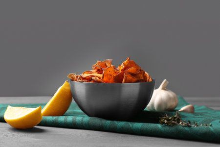 Composition with bowl of sweet potato chips on table against gray background. Space for textの写真素材