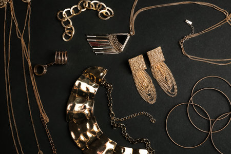 Set of gold jewelry on black background, flat lay