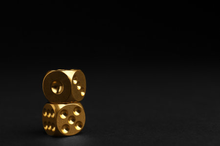 Stacked gold dices on black background. Space for textの写真素材