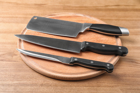 Board with set of knives on wooden backgroundの写真素材