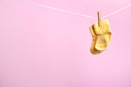 Small socks hanging on washing line against color background, space for text. baby accessoriesの写真素材