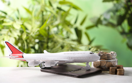 Plane model, passport and coins on table against blurred background. Space for textの写真素材