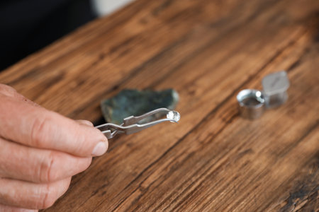 Male jeweler evaluating precious gemstone at table in workshop, closeupの写真素材