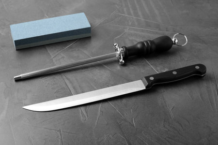 Knife and different sharpeners on gray background