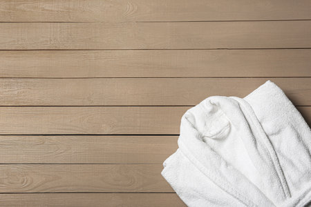 Clean folded bathrobe on wooden background, top view. Space for textの写真素材