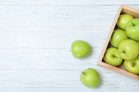 Wooden crate full of fresh green apples on light background, top view. Space for textの写真素材