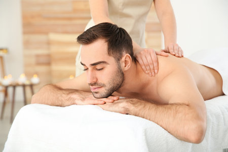 Handsome man receiving back massage in spa salonの写真素材