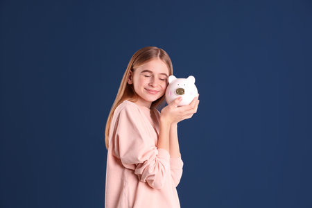 Teen girl with piggy bank on color backgroundの写真素材