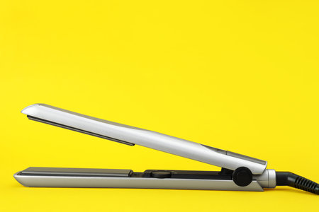 Modern hair iron for straightening on color backgroundの写真素材