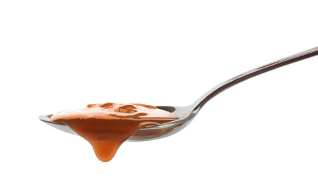 Spoon of tasty caramel sauce isolated on whiteの写真素材
