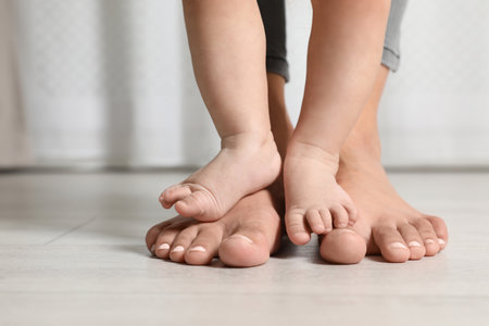 Woman and her little child standing on floor indoors, closeup. Space for textの写真素材