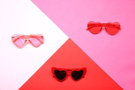 Flat lay composition with heart shaped sunglasses on color backgroundの写真素材