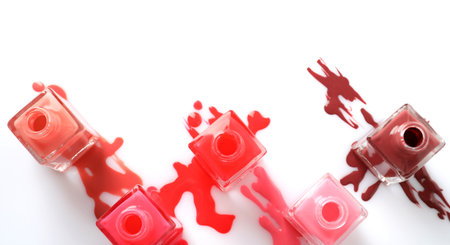 Spilled different nail polishes with bottles on white background, top viewの写真素材