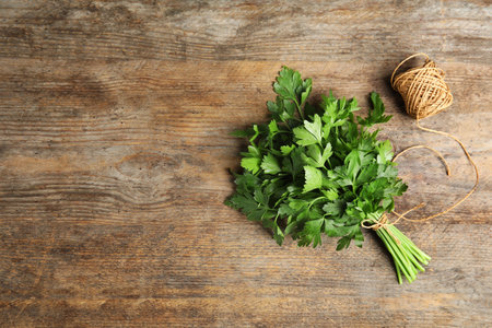 Bunch of fresh green parsley and twine on wooden background, flat lay. Space for textの写真素材