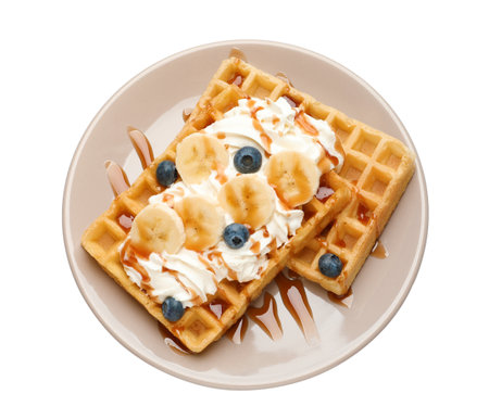 Plate with yummy waffles, whipped cream, blueberries and banana on white background, top viewの写真素材