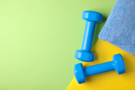 Vinyl dumbbells and towel on color background, flat lay. Space for textの写真素材