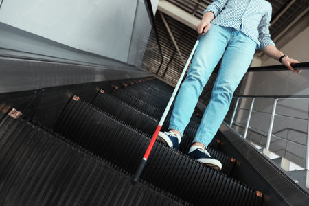 Blind person with long cane on escalator indoorsの写真素材