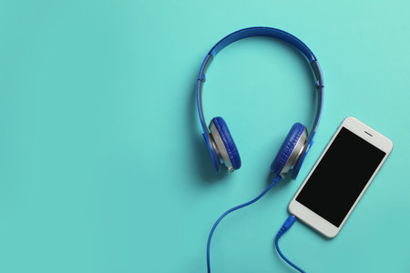 Stylish headphones and modern phone on color background, flat lay. Space for textの写真素材