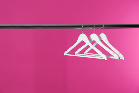 Metal rack with clothes hangers on color background, space for textの写真素材