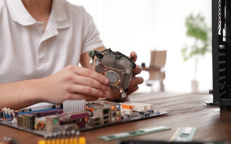 Male technician repairing computer at table indoors, closeup