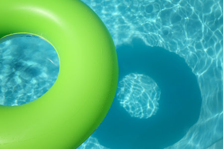 Bright inflatable ring floating in swimming pool on sunny day. Space for textの写真素材