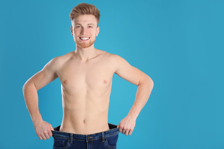Handsome man in oversized jeans on color background. Space for textの写真素材