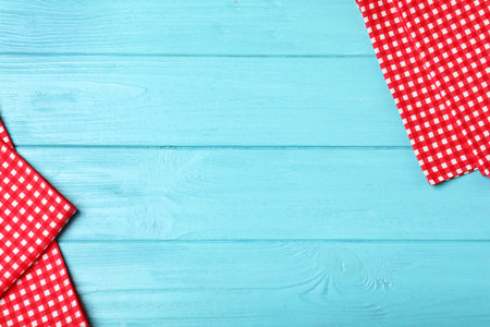Checkered picnic napkins on wooden background, top view. Space for text