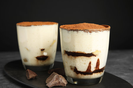 Two glasses of tiramisu cake on table against dark background, closeupの写真素材