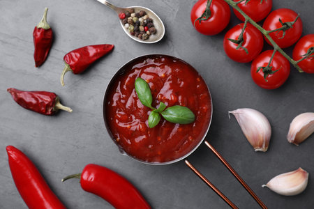 Flat lay composition with pan of chili sauce and ingredients on gray tableの写真素材