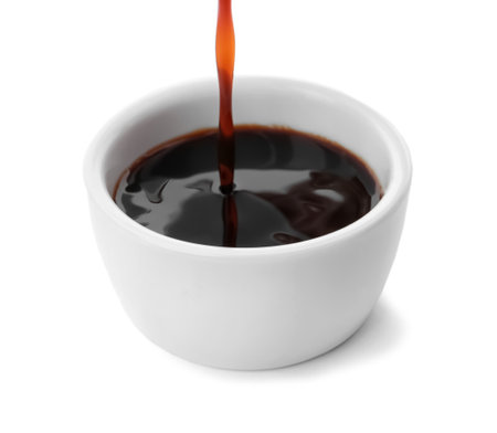 Pouring tasty soy sauce into bowl isolated on whiteの写真素材