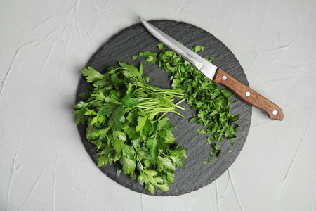 Slate plate with fresh green parsley and knife on gray background, top viewの写真素材