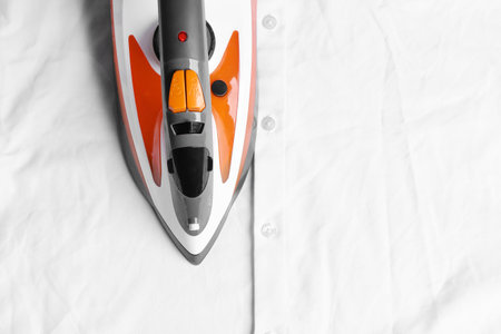 Modern electric iron on wrinkled cloth, top view. Space for textの写真素材