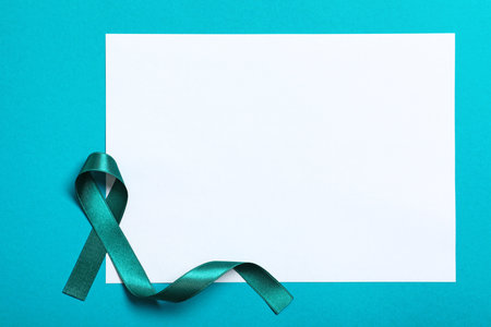 Teal ribbon and blank card on color background, top view. Space for textの写真素材