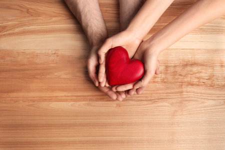 couple holding decorative heart on wooden background, top viewの写真素材