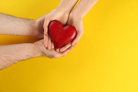Couple holding decorative heart on color background, top view. Space for textの写真素材