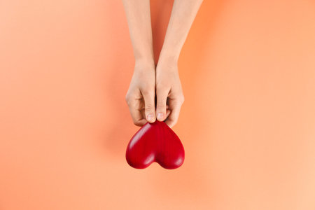 Woman holding decorative heart on color background, top viewの写真素材