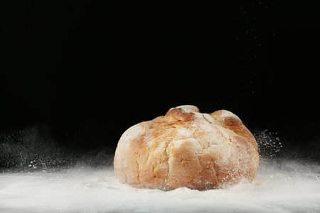Loaf of bread on table against dark background. Space for textの写真素材
