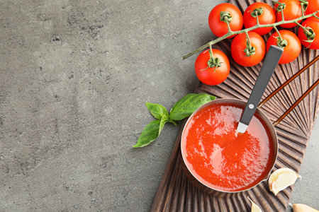 Flat lay composition with pan of sauce and tomatoes on gray table. Space for textの写真素材