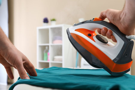 Man ironing clothes on board at home, closeupの写真素材