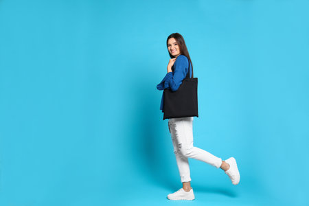 Beautiful young woman with stylish blank eco bag against color background, space for textの写真素材