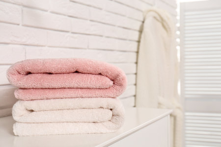 Clean folded towels on table near brick wall. Space for textの写真素材