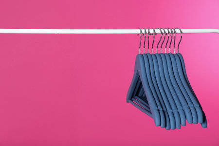 Metal rack with clothes hangers on color background, space for textの写真素材