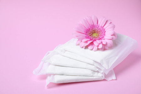 Packed menstrual pads and flower on color background, space for text. Gynecological careの写真素材