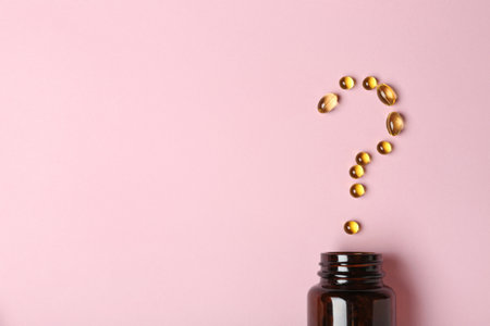 Question mark of cod liver oil capsules and jar on color background, flat lay. Space for textの写真素材