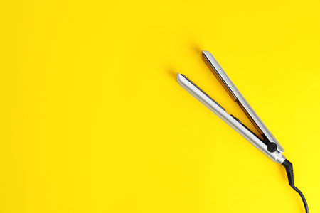 Modern hair iron for straightening on color background, top view with space for textの写真素材