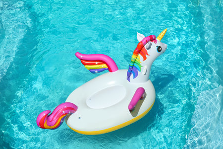 Funny inflatable unicorn ring floating in swimming pool on sunny dayの写真素材