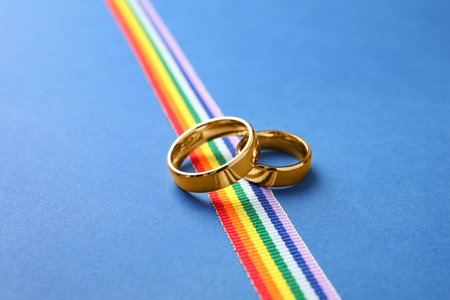 Wedding rings and rainbow ribbon on color background. gay symbolの写真素材