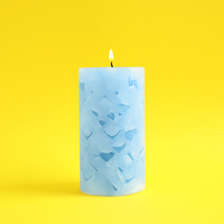 Alight scented wax candle on color backgroundの写真素材